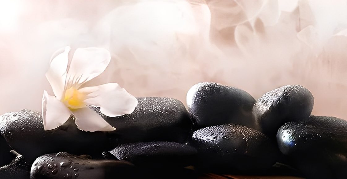 Steaming stones with flower in spa setting.
