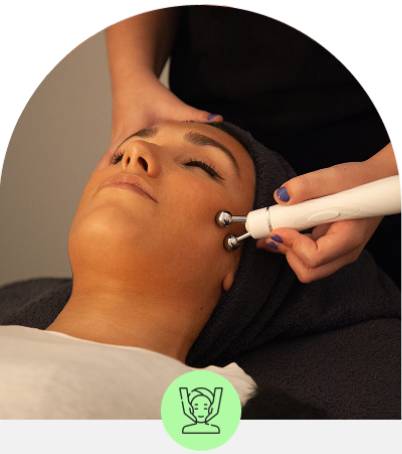 A woman receiving a facial treatment with a handheld device.