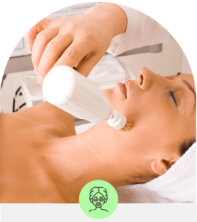 A woman receiving a facial treatment with a white handheld device.