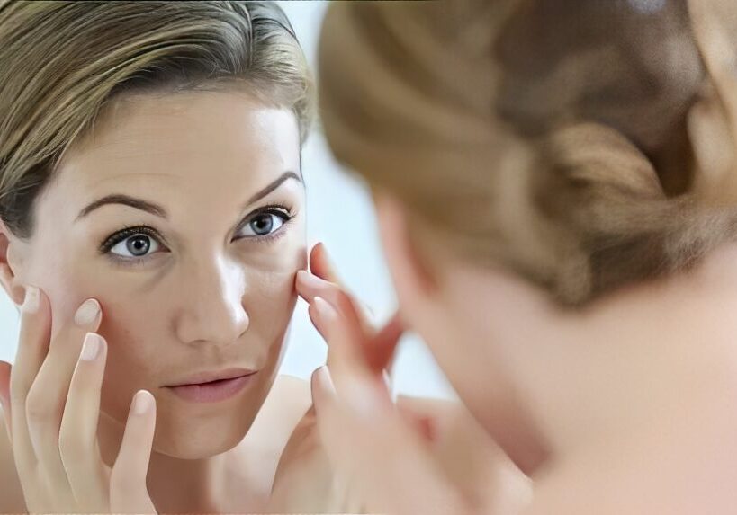 Woman checking under-eye skin in mirror