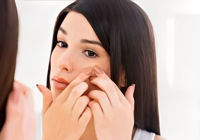 Woman examining face in bathroom mirror.