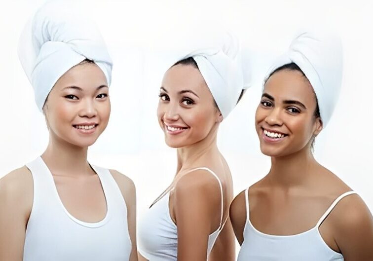 Three women smiling with towels on heads.